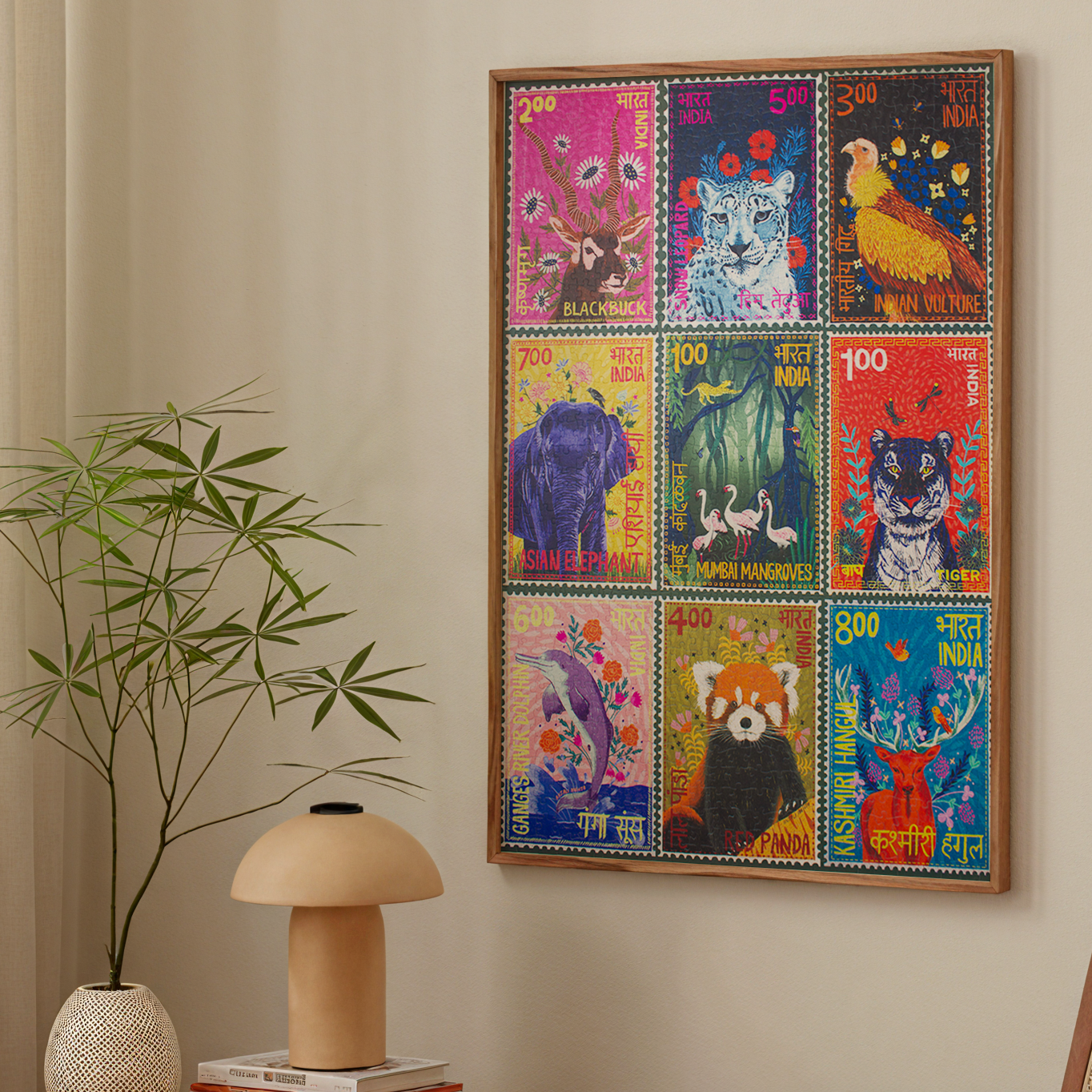 Colorful framed artwork of animal stamps on a wall above a wooden table with a lamp and books, next to a chair.