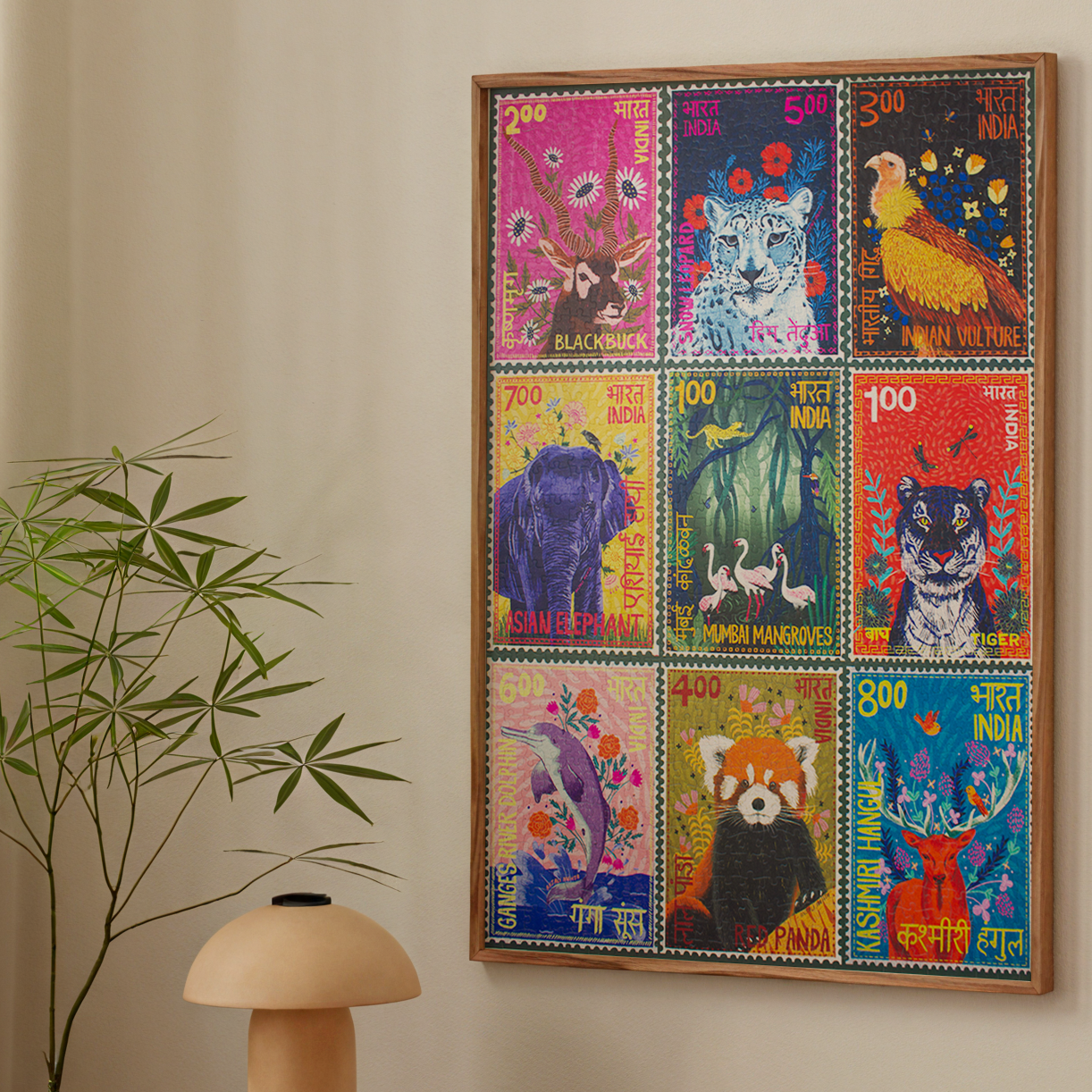 Colorful framed artwork of animal stamps on a wall above a wooden table with a lamp and books, next to a chair.